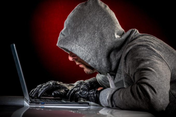 Hooded man on laptop: SoftwareSix Industry News Blog